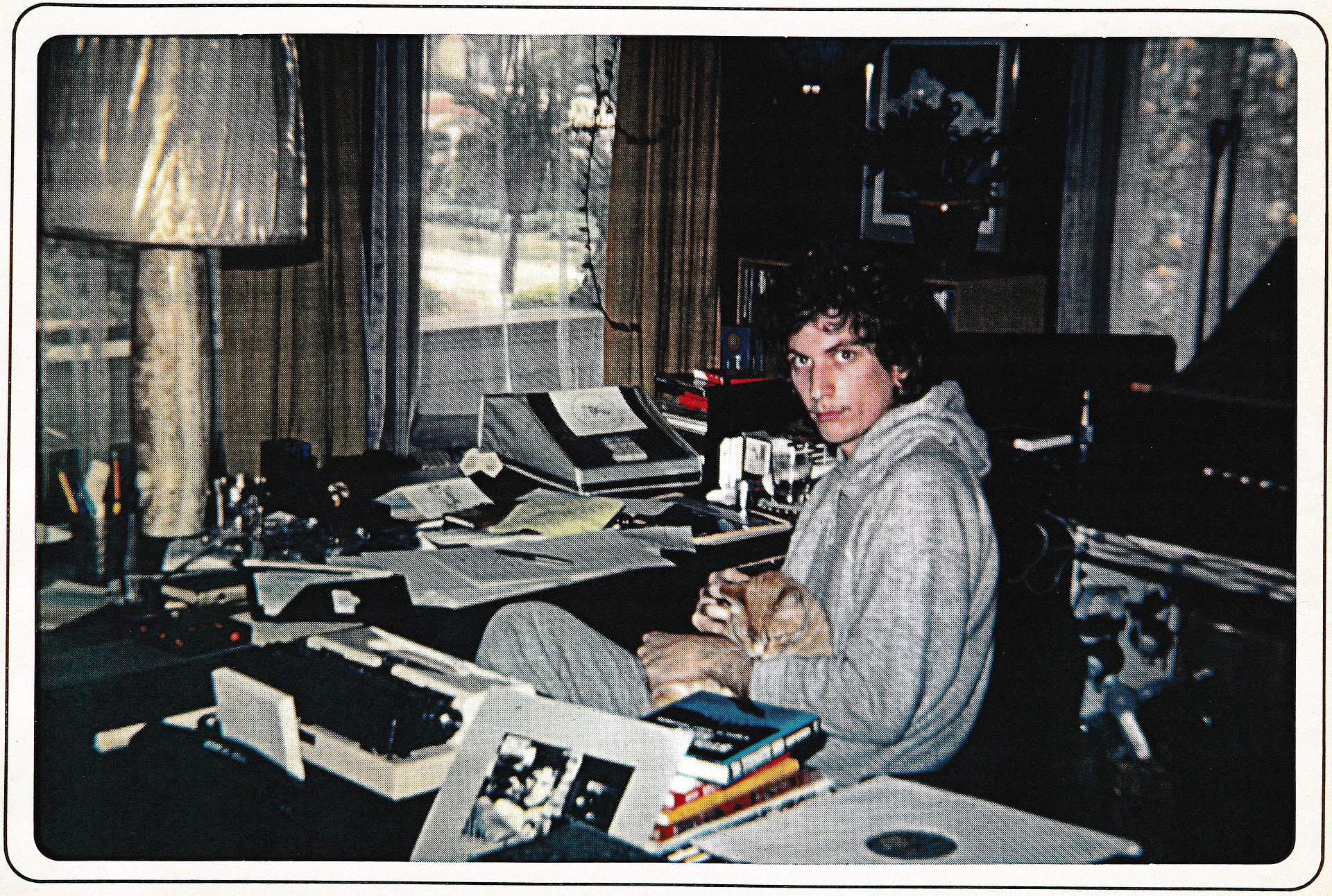 Man surrounded by ancient artifacts with cat on lap.